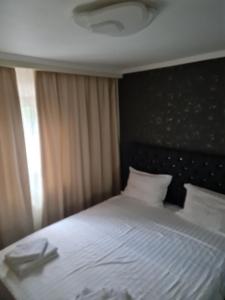 1 dormitorio con cama blanca y cabecero negro en Atlas Unirii, en Buzau