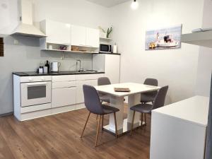 uma cozinha com armários brancos e uma mesa e cadeiras em Holiday home Blue door in Pula em Pula