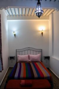 um quarto com uma cama com um cobertor listrado colorido em Riad Darko em Essaouira