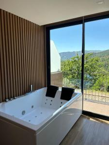 una gran bañera blanca en una habitación con una gran ventana en DOBAU village en Vieira do Minho