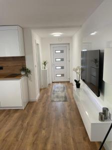 Una sala de estar vacía con gabinetes blancos y un televisor. en Apartman Rawda 2, en Jajce