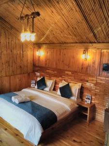 a bedroom with a large bed in a wooden wall at THE WONDERLAND COTTAGES & Cafe in Nārkanda