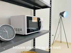 un forno a microonde seduto su uno scaffale accanto ad un orologio di Appartamenti Shardana a Villasimius