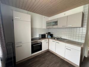 a kitchen with white cabinets and a black oven at kukione Ferienwohnung in Dettingen an der Erms