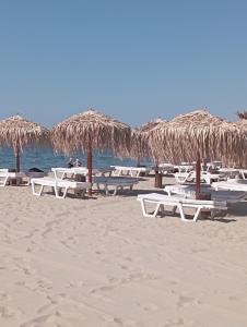 a bunch of chairs and straw umbrellas on a beach at Fantastic Apartment in Sveti Vlas in Sveti Vlas