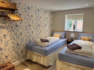 two twin beds in a room with wallpaper at Picket Post House Bed & Breakfast in Catterall