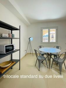 una sala da pranzo con tavolo, sedie e forno a microonde di Appartamenti Shardana a Villasimius