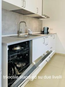 uma cozinha com uma máquina de lavar louça aberta e um lavatório em Appartamenti Shardana em Villasimius