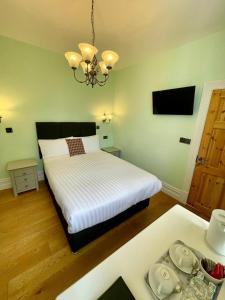 a bedroom with a white bed and a chandelier at Shandon Bells Guest House in Cork