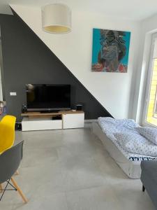 a living room with a flat screen tv and a bed at Apartament z widokiem na jezioro in Rydzewo