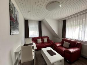a living room with a red couch and chairs at kukione Ferienwohnung in Dettingen an der Erms