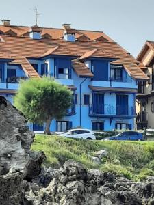 a blue building with cars parked in front of it at El Pinedo AZUL 3 dormitorios in Noja