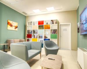 a waiting room with a couch and chairs and a book shelf at Tower Hotel in Busto Arsizio