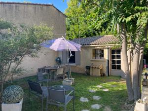 une terrasse avec une table, des chaises et un parasol dans l'établissement Jolie petite maison Avignon - Montfavet, à Montfavet