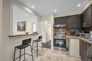 a kitchen with black cabinets and two bar stools at Luxury Renovated 3 Bedroom Home in North York in Toronto