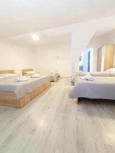 two beds in a room with wooden floors at Eftimija Apartments in Gevgelija