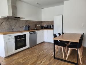 a kitchen with white cabinets and a wooden table at Maison au calme proche océan in Vielle-Saint-Girons