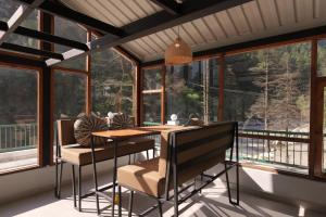 a dining room with a table and chairs and windows at The Trippy Tribe Riverside Hostel Kasol in Kasol