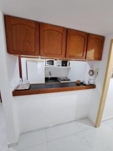 a kitchen with wooden cabinets and a microwave at Areia Preta in Guarapari