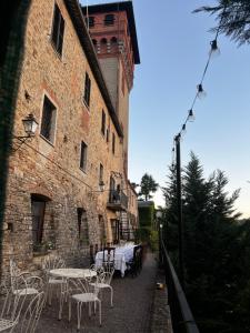 eine Terrasse mit Tischen und Stühlen vor einem Gebäude in der Unterkunft Il Castello di Bubbio in Bubbio