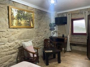 a room with a stone wall with a table and a desk at Os Fentos in Pontevedra