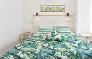 a bedroom with a bed with a green and white comforter at Catalogna10 Rooms in Alghero