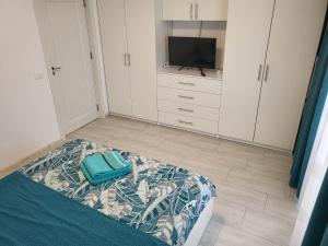 a bedroom with a bed and a tv and white cabinets at Apartament Alex, Dem Rădulescu in Râmnicu Vâlcea