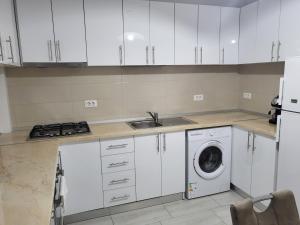 a kitchen with white cabinets and a washing machine at Apartament Alex, Dem Rădulescu in Râmnicu Vâlcea