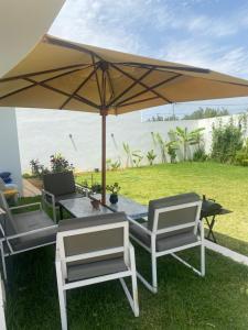 uma mesa e cadeiras debaixo de um guarda-sol na relva em Dar Selima Hammamet em Hammamet