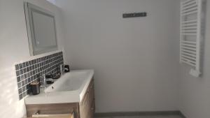 a white bathroom with a sink and a mirror at maison de campagne rénovée in Duras