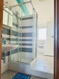 La salle de bains est pourvue d'une douche en verre et d'un lavabo. dans l'établissement Mansarde Marzamemi, à Marzamemi