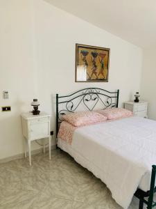 een witte slaapkamer met een bed en twee nachtkastjes bij Da Angela in Orgosolo