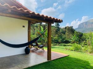 a hammock on a patio with a view of the mountains at Chale Vale das Cachoeiras in Capitólio