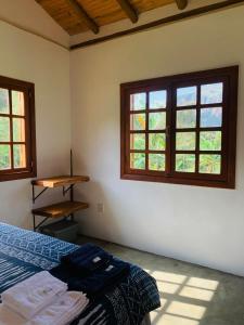 um quarto com duas janelas e uma cama. em Chale Vale das Cachoeiras em Capitólio