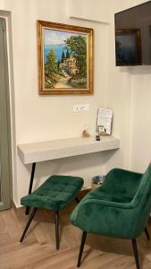 a room with a table and a green chair and a painting at Aesthesis Arxontiko Luxury Rooms in Mirina