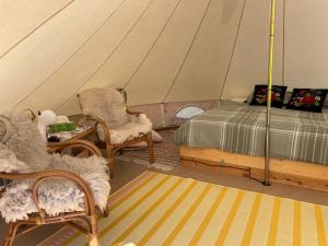 sypialnia z łóżkiem i krzesłami w namiocie w obiekcie Pädaste Aerga Sunrise Glamping w mieście Pädaste