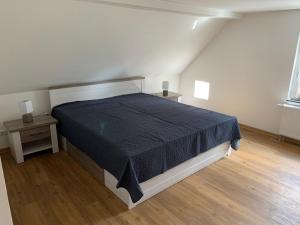 a bedroom with a bed with a black comforter and two tables at Ferienhaus Putzar 45 in Boldekow