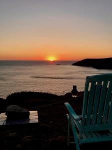 una sedia blu seduta sulla spiaggia a guardare il tramonto di Poecylia a Carloforte