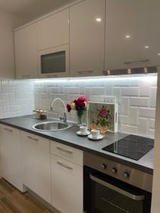 a kitchen with white cabinets and a sink at Apartman Dorotea in Trebinje