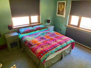 una camera da letto con un letto con un piumone colorato e due finestre di Mountain Suite, Stunning Views, Brecon Beacons a Llanhamlach