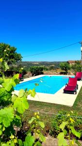 a swimming pool with red lounge chairs next to it at Casinha CB in Casteição