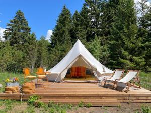 帕達斯特的住宿－Pädaste Aerga Sunset Glamping，一个带椅子和木制甲板的白色帐篷