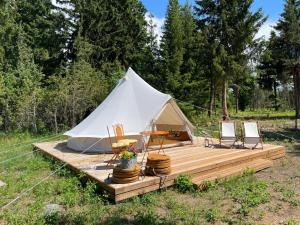 帕達斯特的住宿－Pädaste Aerga Sunset Glamping，木制甲板上的白色帐篷配有椅子和桌子
