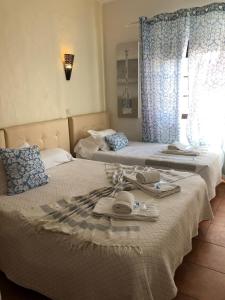 two beds in a bedroom with towels on them at Quartos Abelha in Porto Covo
