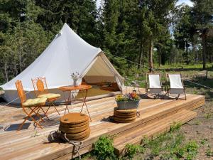 帕達斯特的住宿－Pädaste Aerga Sunset Glamping，木制甲板上的带椅子和桌子的帐篷