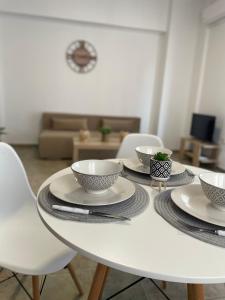 a white table with four bowls and plates on it at Melivia apartments in Ierissos