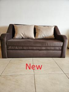 un divano marrone con un nuovo cartello sul pavimento di Apartment Ashton Hall - Sonnenstrand – Ost a Sunny Beach