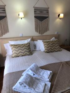 a bedroom with a bed with towels on it at Quartos Abelha in Porto Covo