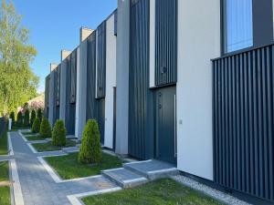 a row of buildings with green doors and trees at Cukura Loft in Jelgava