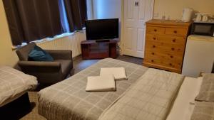 - une chambre avec un lit, une télévision et une chaise dans l'établissement Shamrock Guest House, à Gravesend